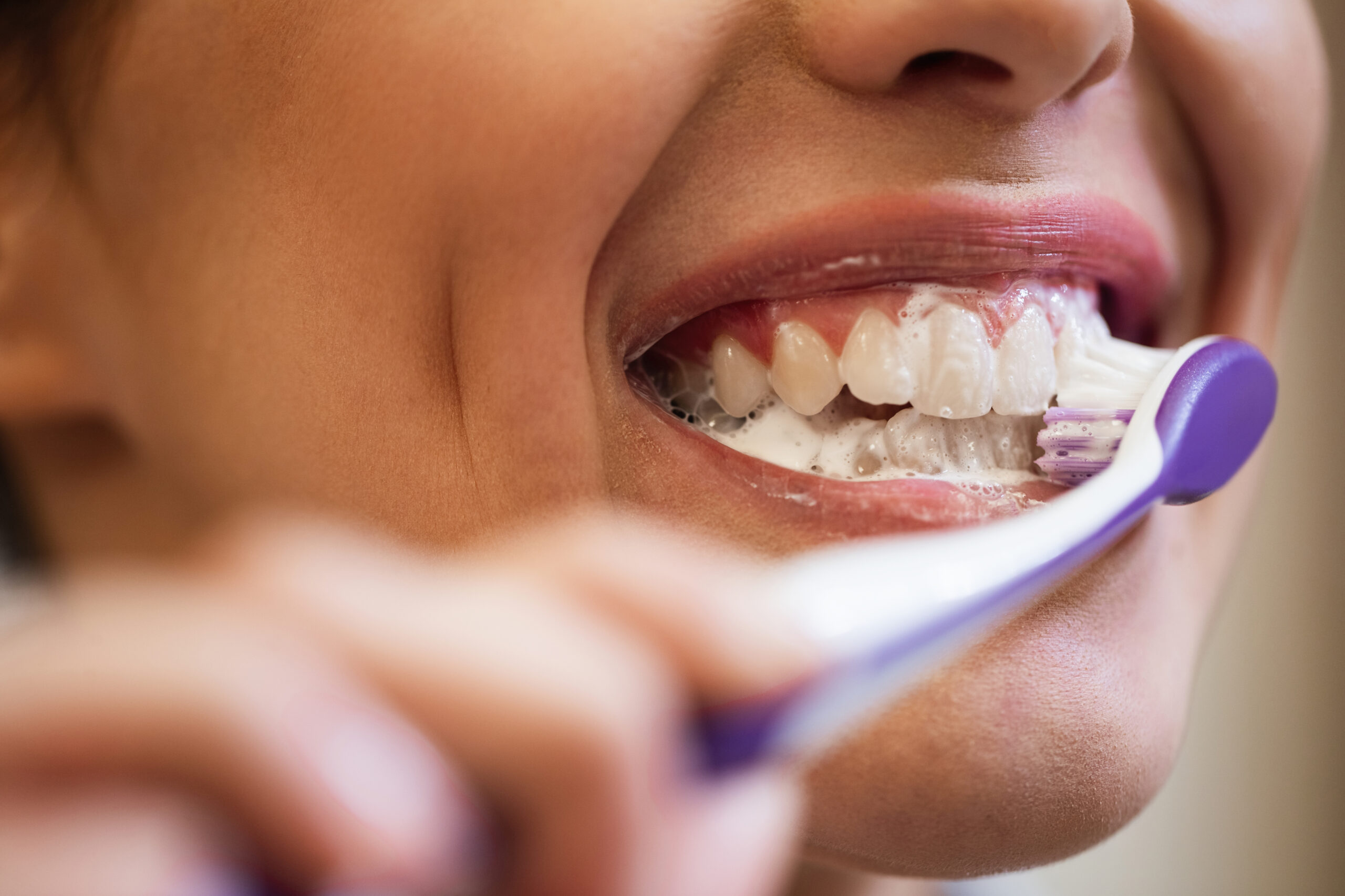 Close-up of of woman using toothbrush while cleaning her teeth.